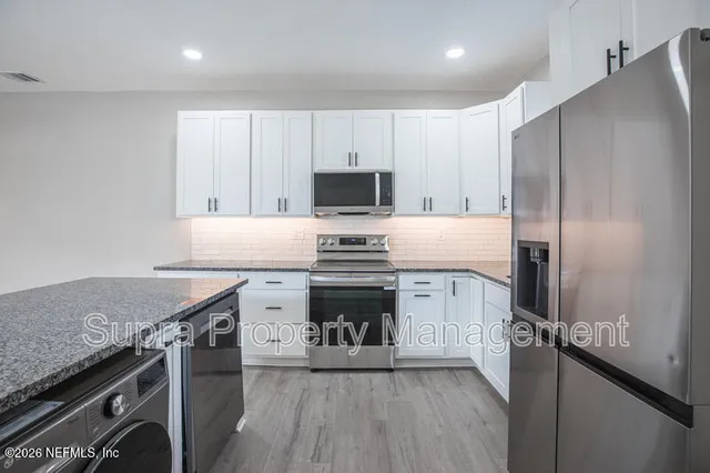a kitchen with granite countertop a stove sink and refrigerator