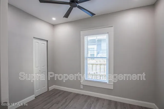 a view of an empty room with wooden floor and a window