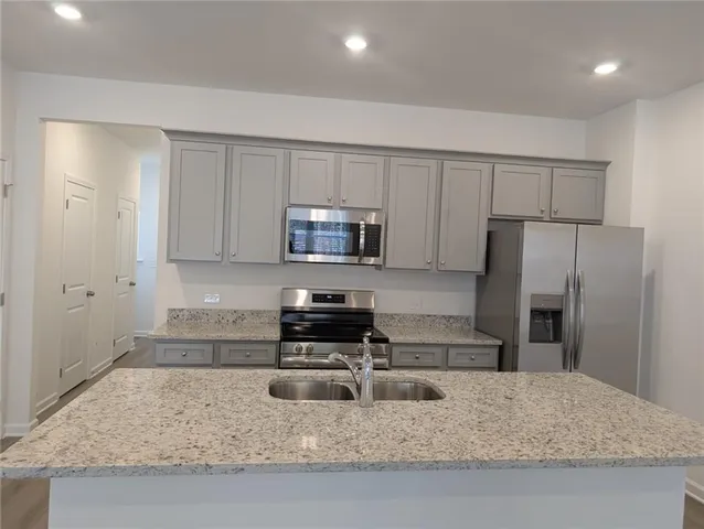a kitchen with granite countertop a refrigerator sink and stove