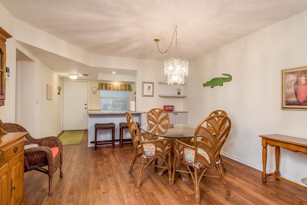 952 Virginia Street, Unit 105 Dunedin, FL 34698 - Photo 9 of 26 a dining room with furniture a chandelier and wooden floor