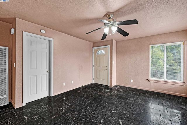 a view of an empty room with window and chandelier fan