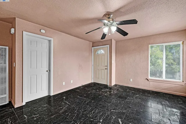 a view of an empty room with window and chandelier fan