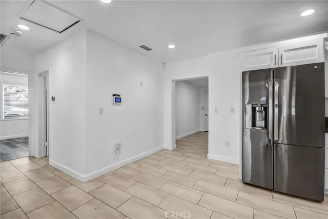 a view of a refrigerator in kitchen and an empty room
