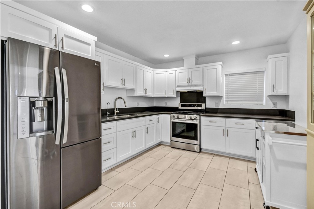 3913 Walnut Street Baldwin Park, CA 91706 - Photo 10 of 25 a kitchen with stainless steel appliances granite countertop a refrigerator sink and white cabinets