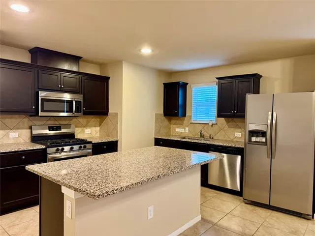 a kitchen with stainless steel appliances granite countertop a sink refrigerator and microwave