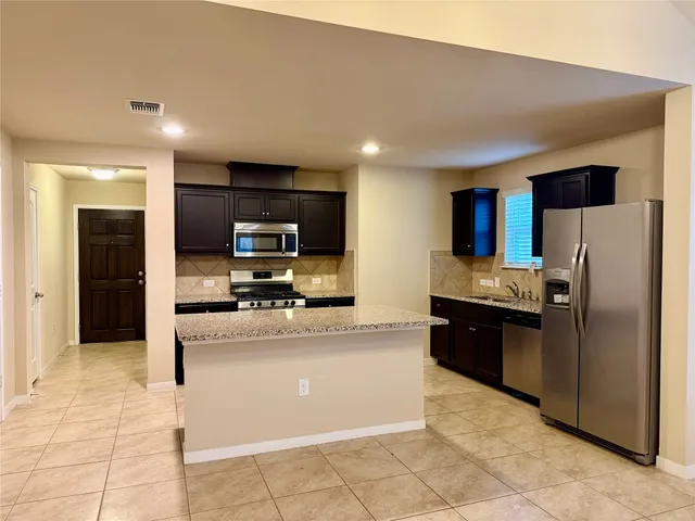 a large kitchen with a large counter top stainless steel appliances and cabinets