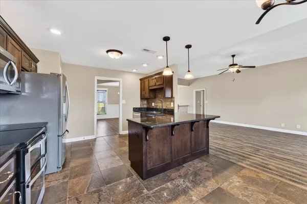 a large kitchen with stainless steel appliances granite countertop a stove and a refrigerator