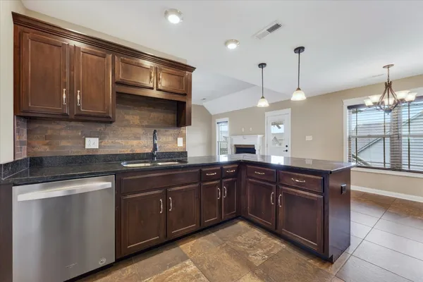 a kitchen with stainless steel appliances granite countertop wooden cabinets a stove a sink and dishwasher