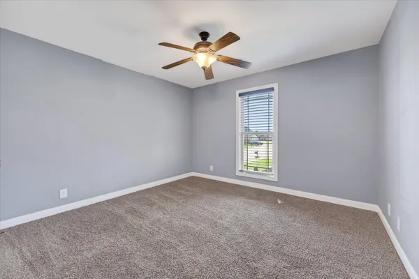 an empty room with window and ceiling fan