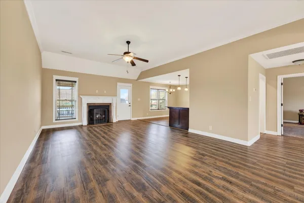 an empty room with wooden floor fireplace and windows