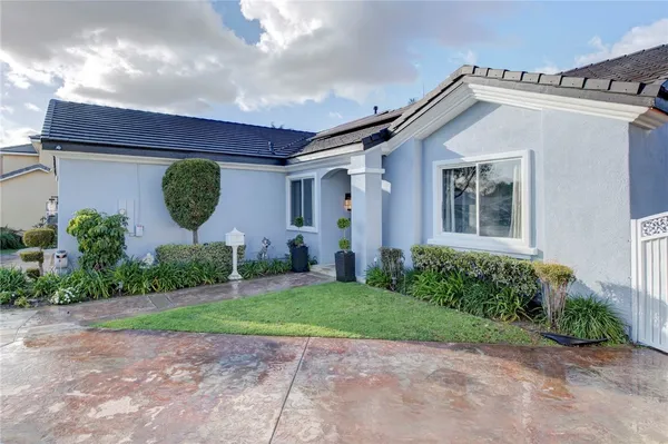 a view of a house with a small yard and a large tree