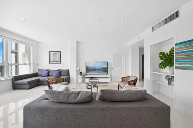a living room with furniture flat screen tv and large windows