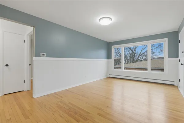 a view of empty room with wooden floor and fan