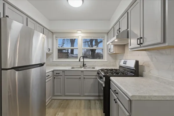 a kitchen with stainless steel appliances granite countertop a sink stove and refrigerator