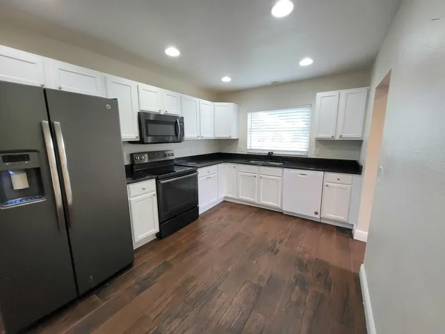 a kitchen with granite countertop a refrigerator sink and microwave