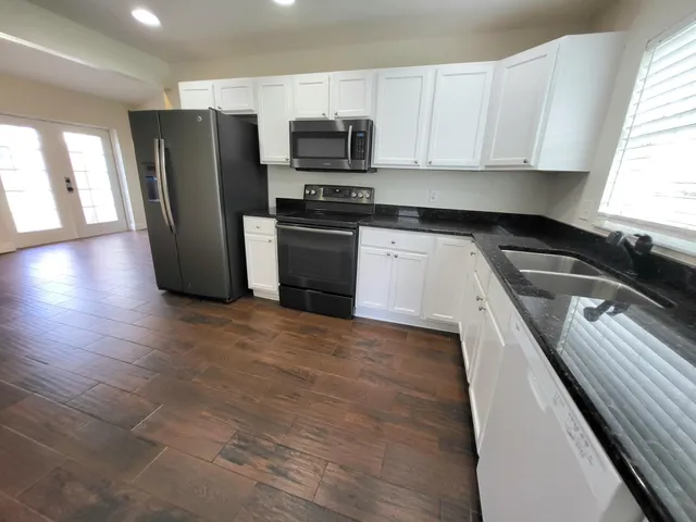 a kitchen with granite countertop a refrigerator and a stove top oven