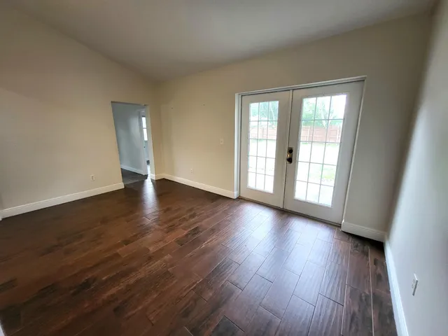 a view of an empty room with wooden floor and a window