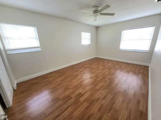 a view of an empty room with wooden floor and a window
