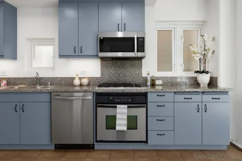 a kitchen with granite countertop white cabinets and stainless steel appliances
