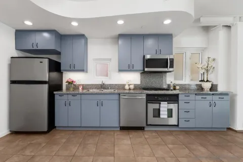 a kitchen with granite countertop a refrigerator and a stove top oven