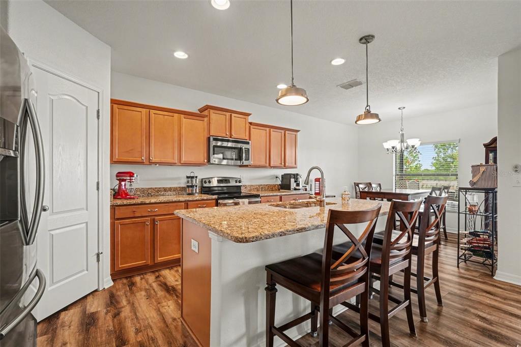 1606 Acadia Harbor Place Brandon, FL 33511 - Photo 11 of 38 a kitchen with stainless steel appliances granite countertop a stove a refrigerator a kitchen island a sink cabinets and a refrigerator