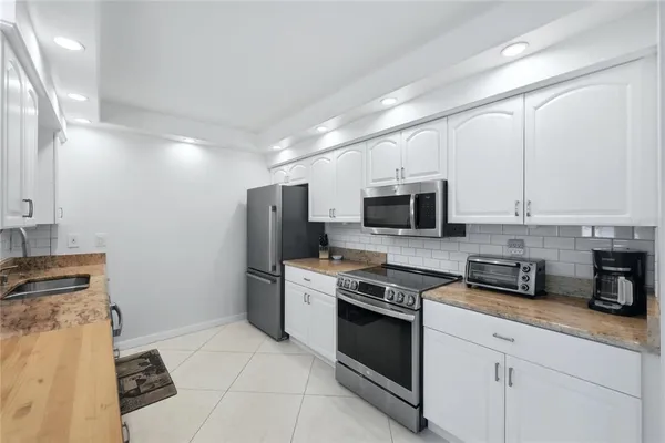 a kitchen with stainless steel appliances granite countertop a stove a sink and a refrigerator