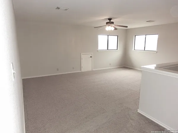 an empty room with windows and chandelier fan
