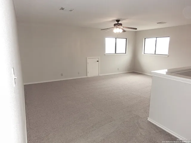 an empty room with windows and chandelier fan
