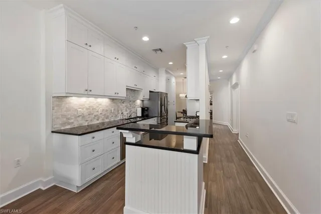 a kitchen with granite countertop a sink appliances cabinets and wooden floor