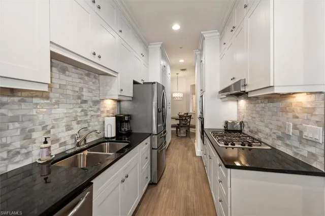 a kitchen with granite countertop a sink stainless steel appliances and cabinets