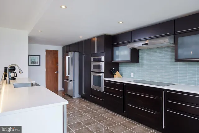 a kitchen with stainless steel appliances kitchen island granite countertop a refrigerator and a sink
