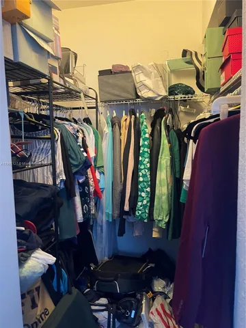 a view of walk in closet with clothes and shoes