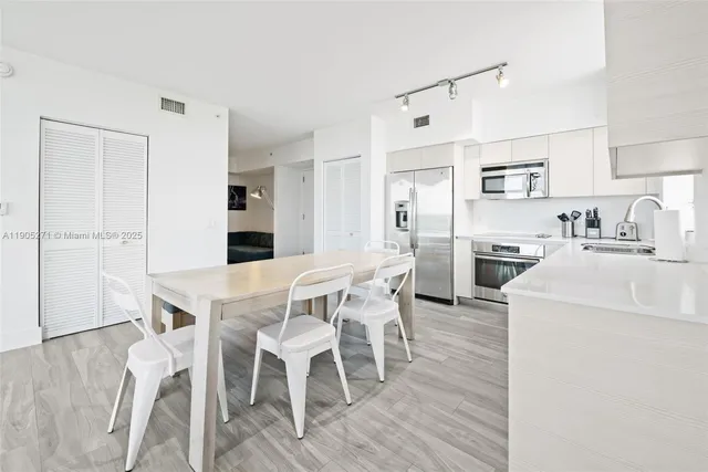 a kitchen with a dining table chairs refrigerator and cabinets