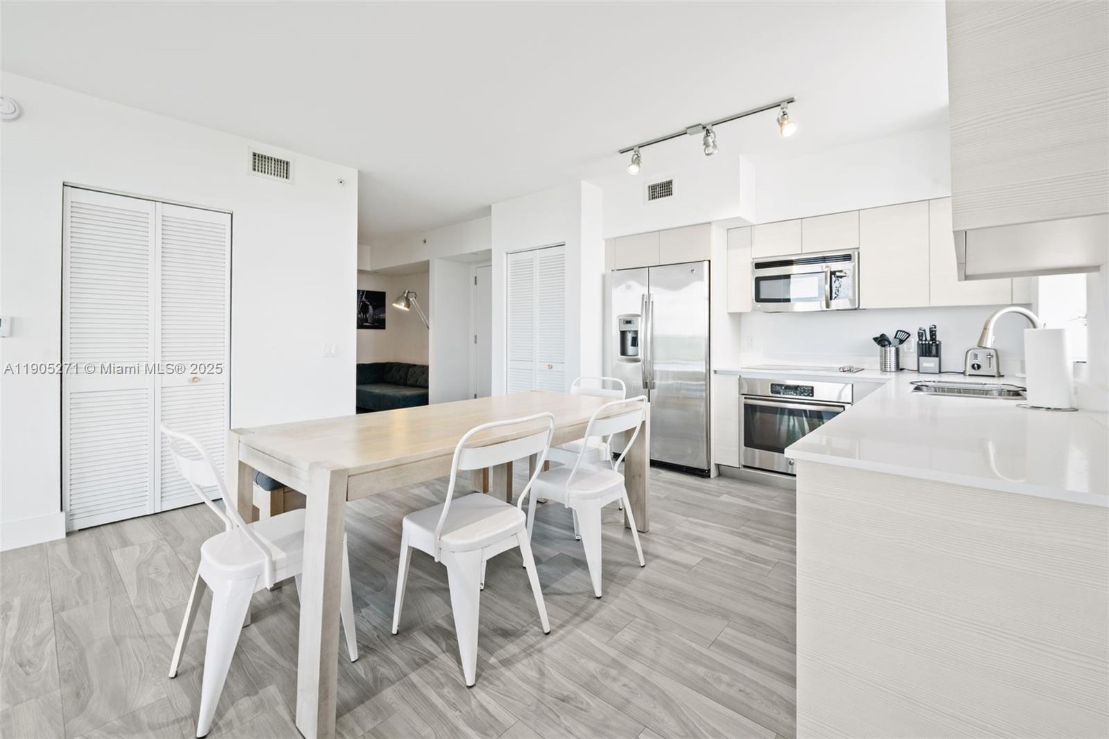 4250 Biscayne Boulevard, Unit 1009 Miami, FL 33137 - Photo 8 of 23 a kitchen with a dining table chairs refrigerator and cabinets