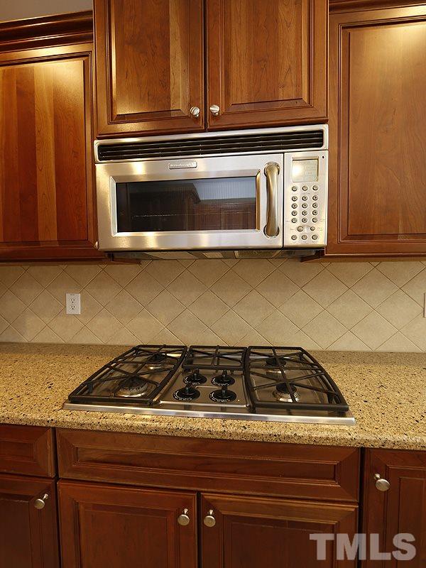 3324 Queensland Road Raleigh, NC 27614 - Photo 6 of 25 A close up of the cooktop and microwave. You can also see the tile backsplash.