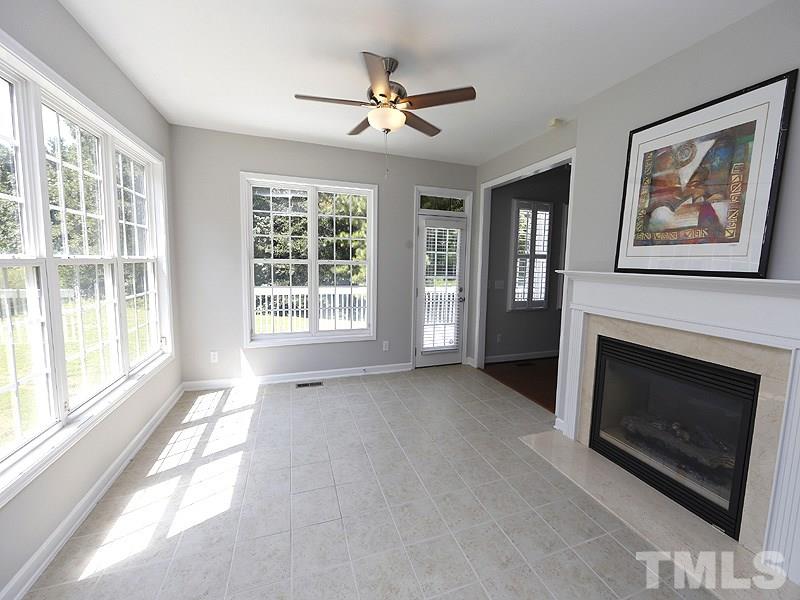 3324 Queensland Road Raleigh, NC 27614 - Photo 9 of 25 The sunroom with tile floor and walls of windows is a cozy place to gather. There is a see-through fireplace with gas logs that connects to the family room on the other side.