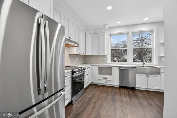 a large kitchen with granite countertop a large window a sink and stainless steel appliances