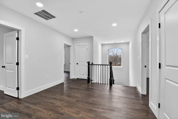 a view of an empty room with wooden floor and white doors