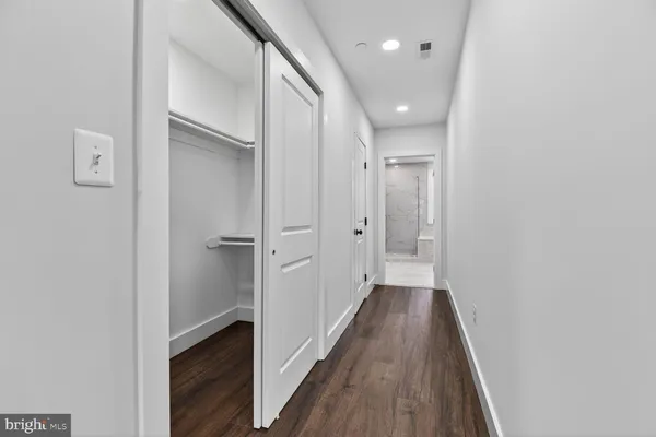 a view of a hallway with wooden floor and a bathroom