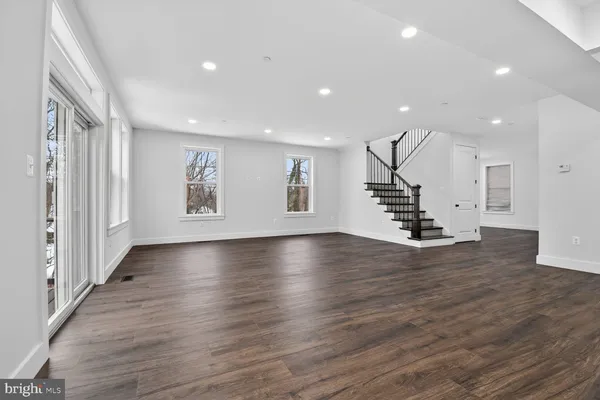 an empty room with wooden floor windows and staircase