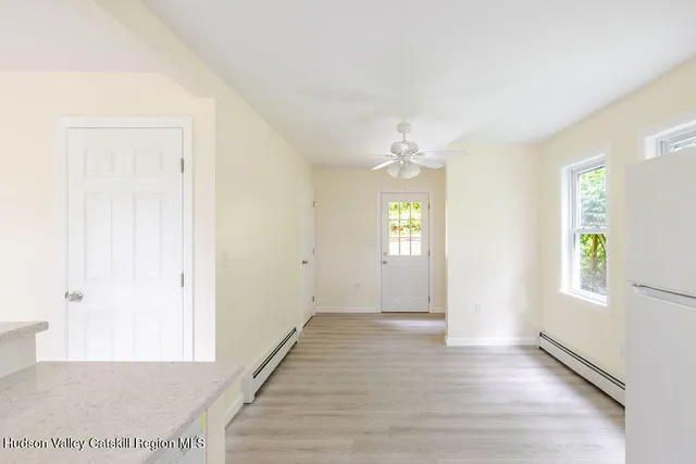 a view of an empty room with window and wooden floor