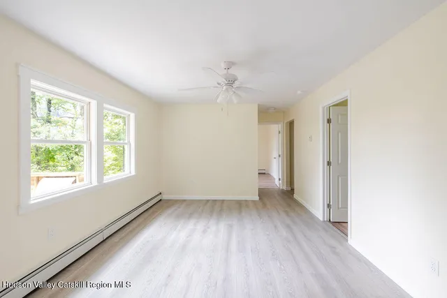 a view of an empty room with wooden floor and a window