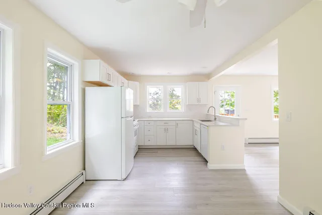 a kitchen with a white refrigerator freezer a sink and dishwasher with wooden floor