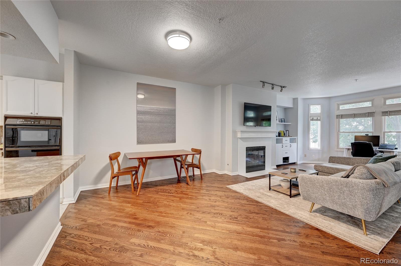45 Jackson Street, Unit D Denver, CO 80206 - Photo 8 of 26 a living room with furniture a fireplace a flat screen tv and kitchen view