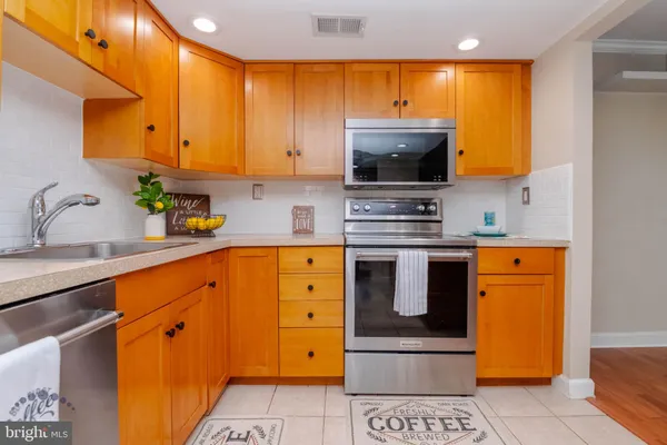 a kitchen with stainless steel appliances granite countertop a refrigerator a sink dishwasher and wooden cabinets with island