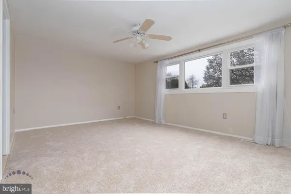 an empty room with windows and ceiling fan