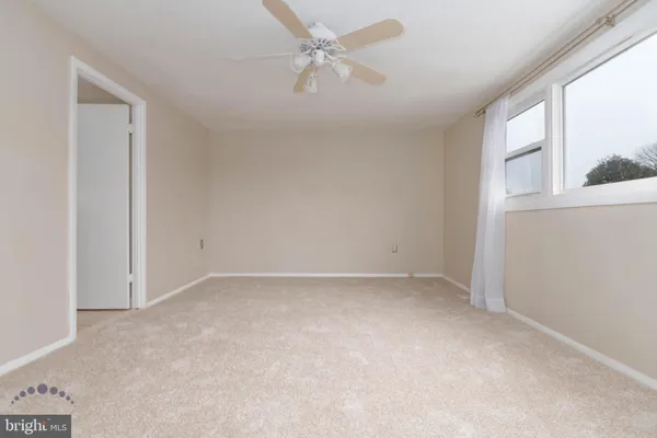 an empty room with a window and a ceiling fan