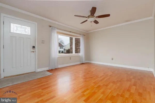 a view of an empty room with wooden floor and a ceiling fan