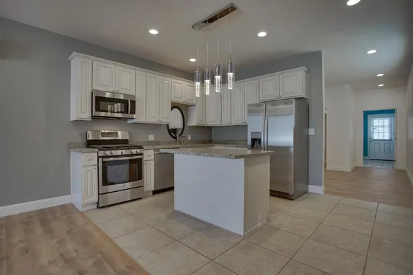 a kitchen with kitchen island granite countertop a stove top oven microwave and cabinets
