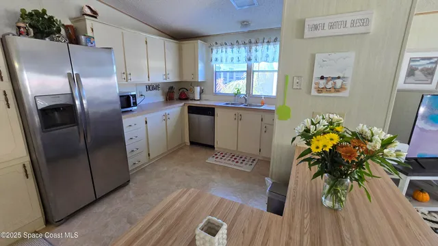 a kitchen with stainless steel appliances a refrigerator a sink a counter space and wooden floor